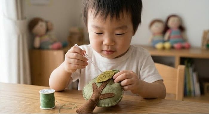 フェルトで作った木のぬいぐるみに、真剣な表情で針を通す小さな子ども