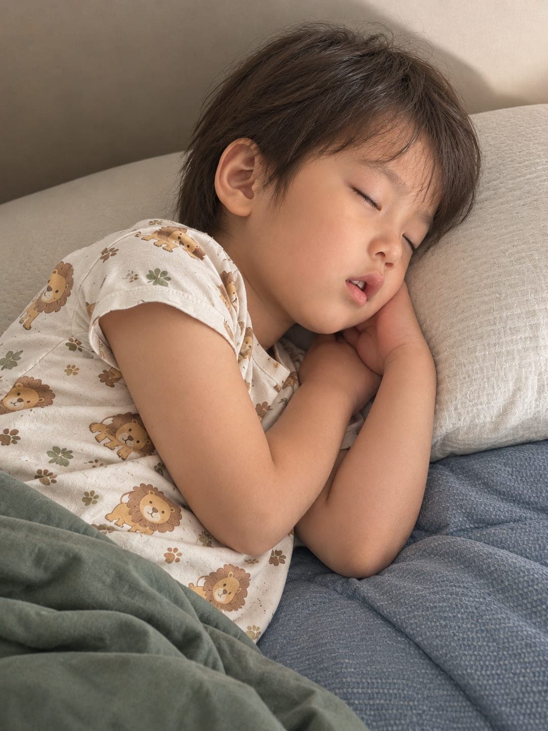 ライオン柄のパジャマで、枕に頭をのせて静かに眠っている子ども