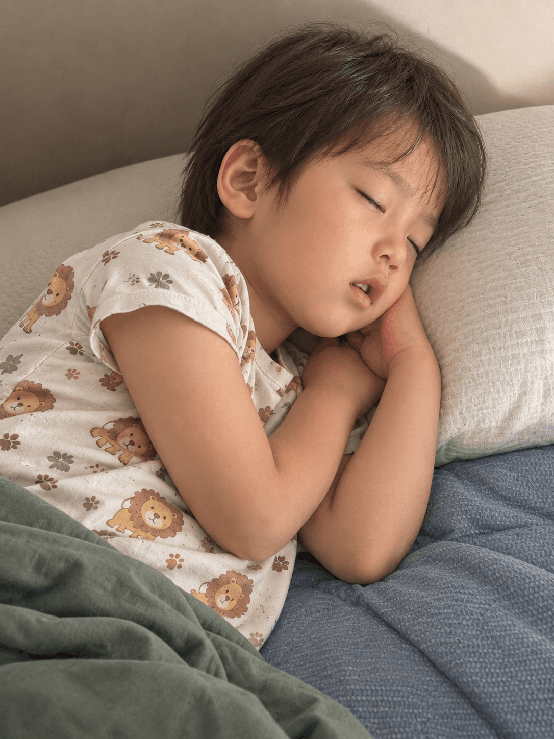 ライオン柄のパジャマで、枕に頭をのせて静かに眠っている子ども