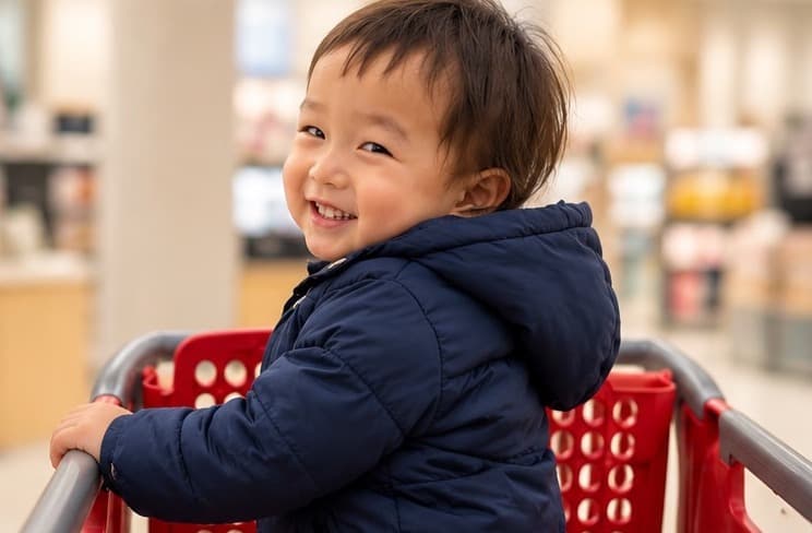 ショッピングカートに掴まって、うれしそうに振り返る男の子