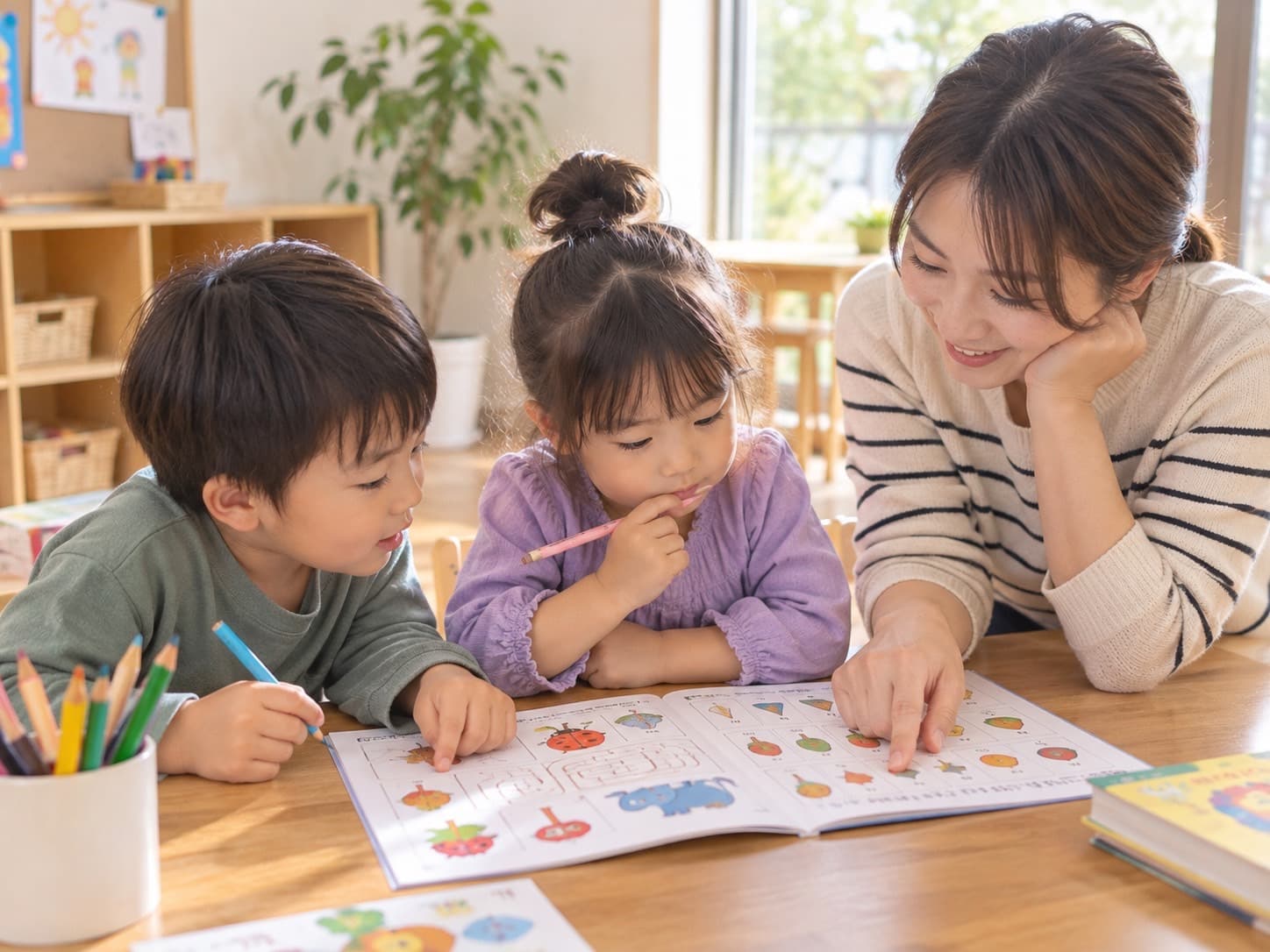 お母さんと一緒に、ワークブックの絵を見ながら、集中して取り組んでいる2人の子ども