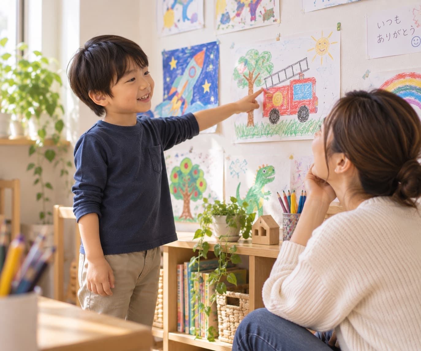 壁に飾った自分の絵を指差して、お母さんに説明している男の子