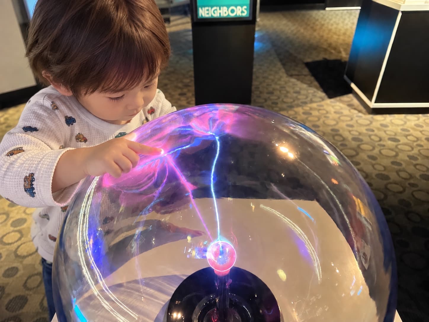 科学館のプラズマボールに指で触れて、じっと見入っている男の子