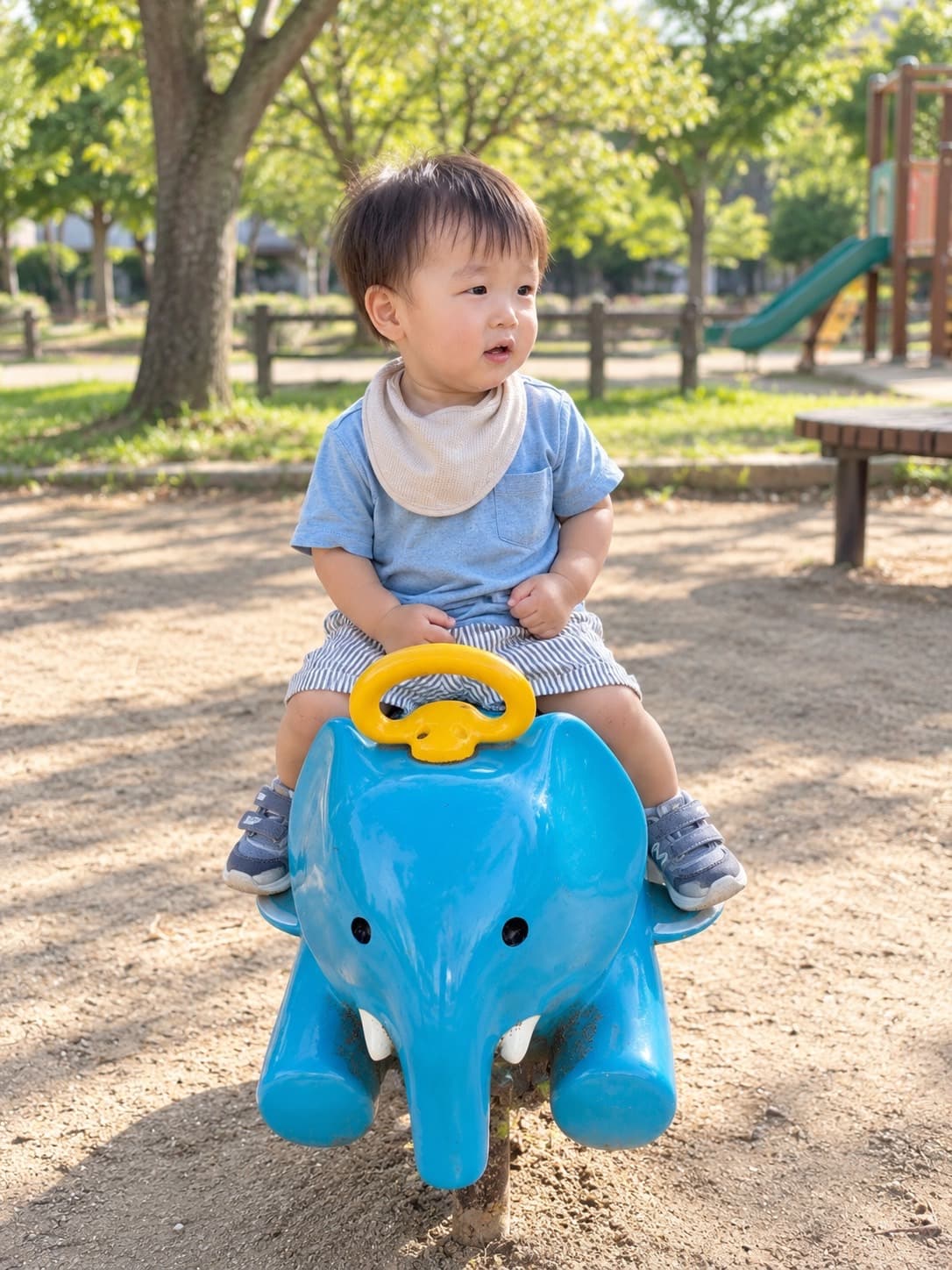 公園のぞうの形の遊具にまたがって、まわりを見ている男の子