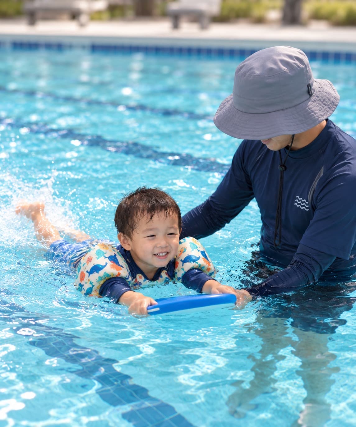 指導者に支えられながら、浮き具とビート板でバタ足の練習をしている男の子